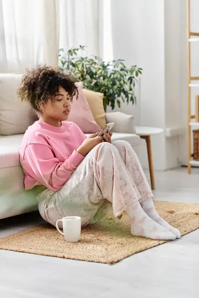 Una giovane donna si gode un momento di pace a casa, immersa nel suo telefono. — Foto stock