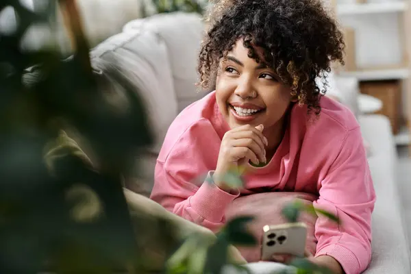 A young woman relaxes on the couch, enjoying a cheerful moment at home. — Stock Photo