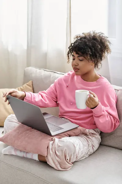 She sips coffee while working on her laptop, enjoying a cozy day at home. — Stock Photo