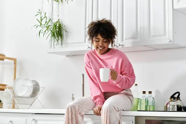 A cheerful woman savors her coffee, radiating warmth in her home. — Stock Photo