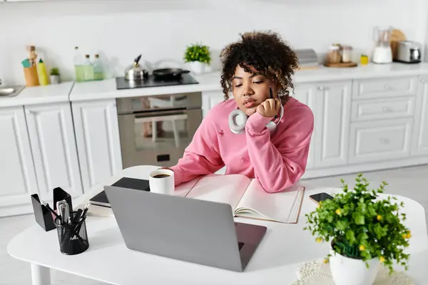 Una giovane donna si rilassa a casa, lavorando sul suo computer portatile con una tazza di caffè caldo. — Foto stock