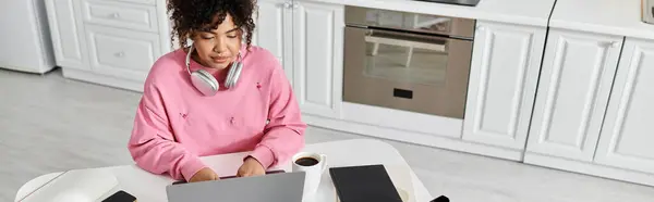 A young woman relaxes while working on her laptop in a stylish kitchen. — Stock Photo