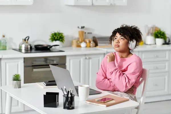 A young woman enjoys her time at home, lost in thought with headphones on. — Stock Photo
