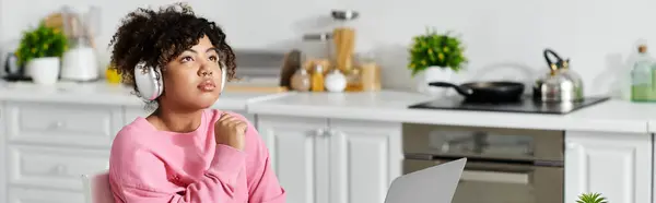 Relajándose en casa, una joven se sumerge en la música mientras trabaja. - foto de stock