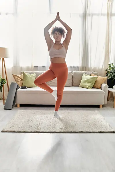 A graceful woman balances in a yoga pose, surrounded by warmth and comfort. — Stock Photo