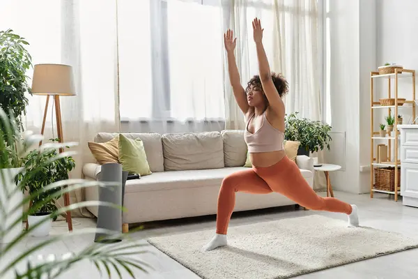 A young woman engages in yoga, showcasing strength and balance in her living space. — Stock Photo