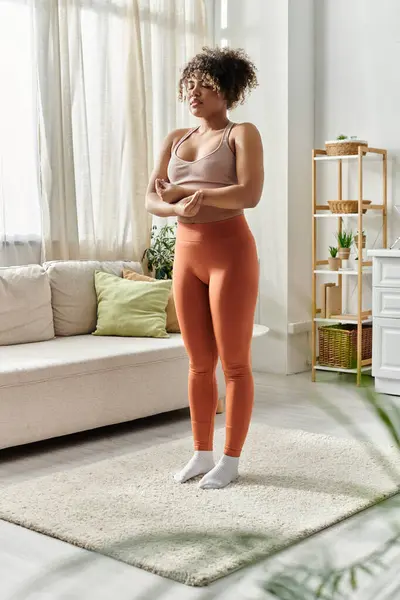 A young woman stands thoughtfully in her stylish living room. — Stock Photo