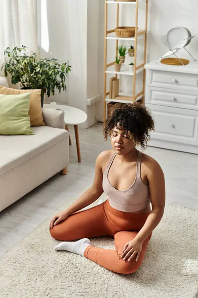 A young woman sits peacefully on a soft rug, lost in thought at home. — Stock Photo