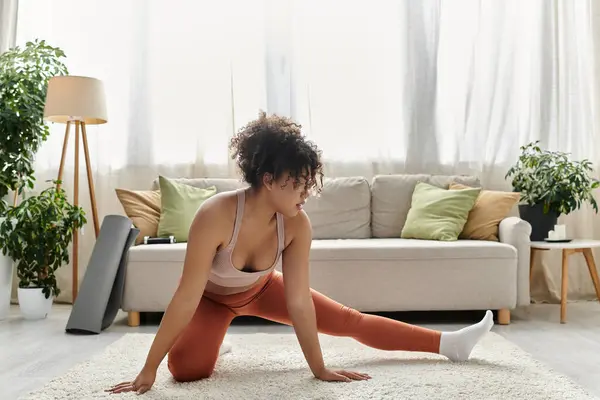 A young woman stretches gracefully on the floor in her relaxing home space. — Stock Photo