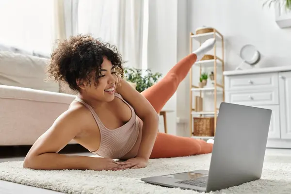 Woman relaxes on the floor, engaging with her laptop in a bright living space. — Stock Photo