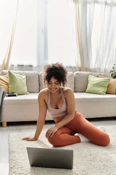 A young woman happily engages with her laptop in a cozy living room. — Stock Photo