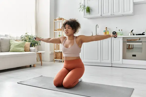 A beautiful woman exercises with weights in her cozy home. — Stock Photo