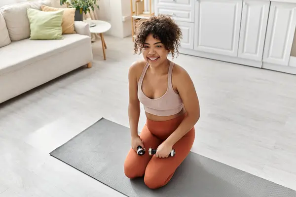 Smiling woman engages in a workout routine on her yoga mat at home. — Stock Photo