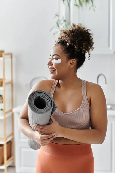 A woman embraces her yoga mat, radiating joy and tranquility in her home. — Stock Photo