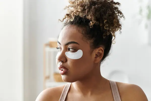 A woman relaxes at home with under eye masks, embracing a peaceful self care moment. — Stock Photo