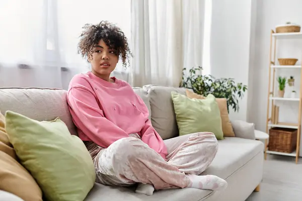 Relaxing on the sofa, a young woman embraces a peaceful moment at home. — Stock Photo