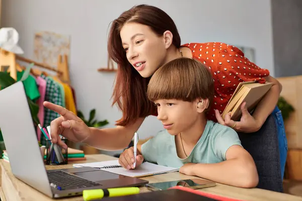 A mother engages with her son, guiding him as he learns at their cozy workspace. — Stock Photo