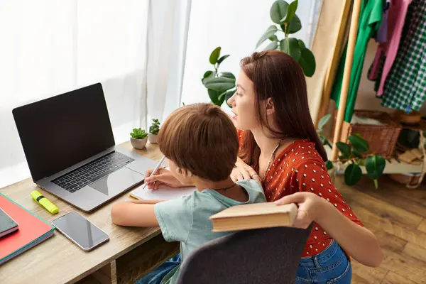 A caring mother assists her son with a lesson at their home workspace. — Stock Photo