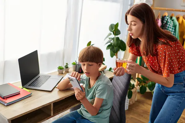 A mother shares a special moment with her son while he focuses on his device. — Stock Photo