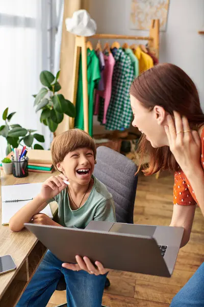 Una madre condivide risate con il figlio ipoacusia mentre usa un computer portatile. — Foto stock