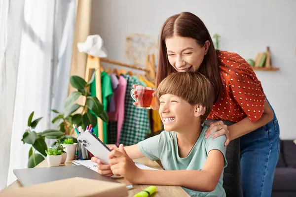 A mother shares a sweet moment with her son while he plays with a smartphone. — Stock Photo