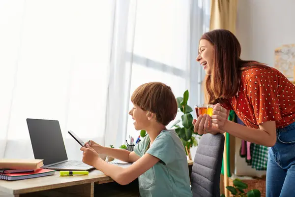 A mother shares laughter and connection with her hearing impaired son at their cozy desk. — Stock Photo