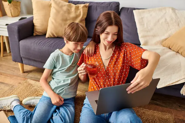 Eine Mutter und ihr Sohn genießen die gemeinsame Zeit, lächeln und beschäftigen sich mit einem Laptop. — Stockfoto