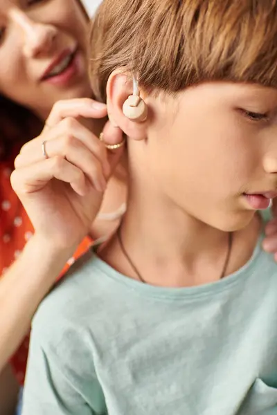 A mother gently helps her hearing impaired son with his hearing device. — Stock Photo