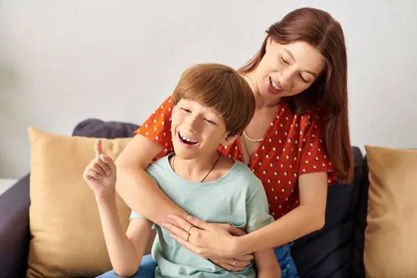 Una madre y su hijo con problemas auditivos comparten un momento alegre juntos. - foto de stock