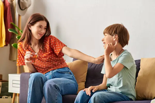 A mother relaxes on the couch, enjoying quality time with her hearing impaired son. — Stock Photo