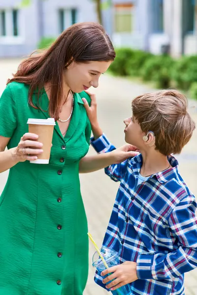 A mother smiles while interacting with her son, who uses hearing aids. — Stock Photo