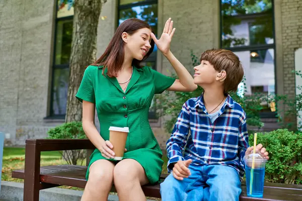 Una madre y su hijo con discapacidad auditiva comparten un momento tierno al aire libre. - foto de stock