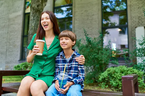 A mother and her son share laughter while enjoying drinks outdoors. — Stock Photo