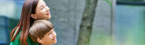 A mother embraces her hearing impaired son in a serene park filled with greenery. — Stock Photo