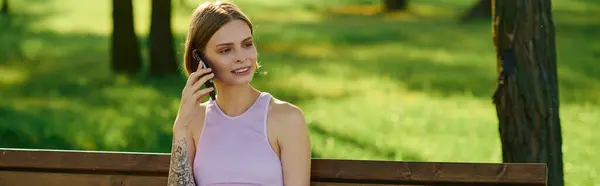 A young woman relaxes on a bench, engaged in a phone conversation surrounded by nature. — Stock Photo