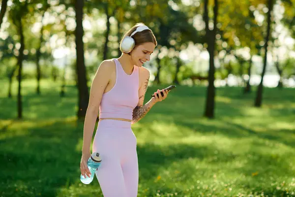 Une femme joyeuse écoute de la musique alors qu'elle se promène dans un parc verdoyant. — Photo de stock