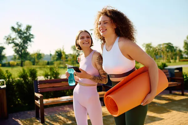 A happy couple connects while carrying yoga mats and water bottles in a park. — Stock Photo