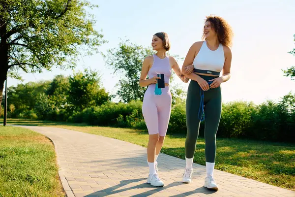 Coppia amorevole passeggia mano nella mano, sorridendo sotto il sole in un parco lussureggiante. — Stock Photo