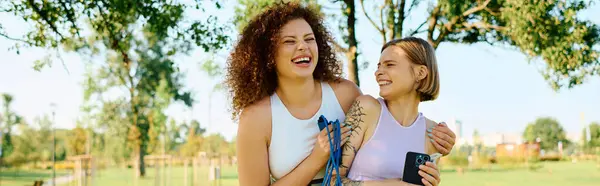 Two women laugh and connect while relaxing in the vibrant park. — Stock Photo