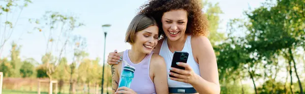 Dos mujeres comparten un momento de alegría en el parque, absortas en la compañía de los demás - foto de stock