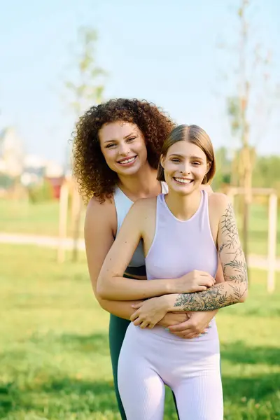 Duas mulheres abraçam calorosamente, cercadas por vegetação e sol no parque. — Fotografia de Stock