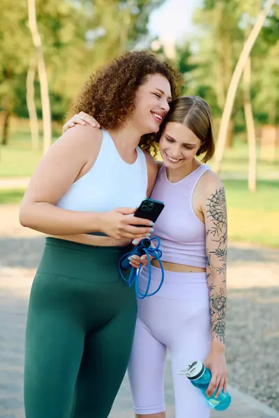 A joyful couple shares laughter while looking at a phone in the park. — Stock Photo
