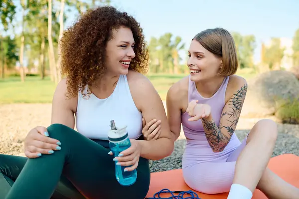 Two women laugh and share joyful moments while relaxing outdoors. — Stock Photo