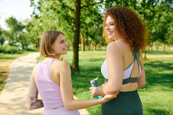 Two women share a warm moment in the park, embracing while walking happily. — Stock Photo