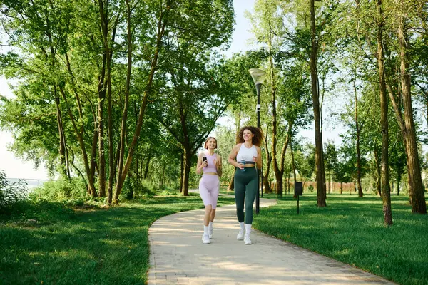 A cheerful lesbian couple enjoys jogging in a vibrant park on a sunny day. — Stock Photo