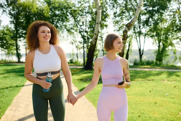 A joyful couple walks hand in hand through a vibrant park on a sunny day. — Stock Photo