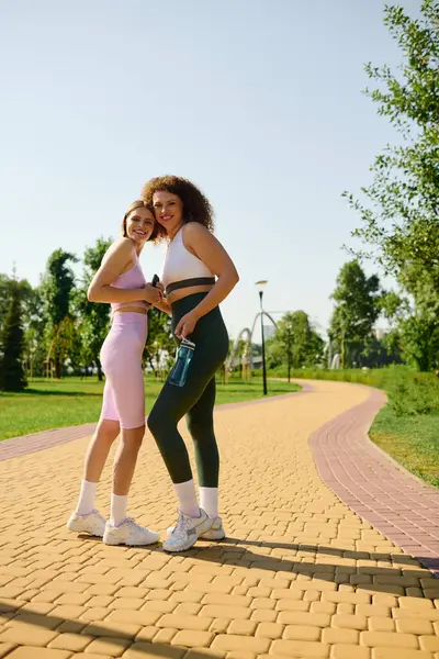 Two women share a joyful moment while exercising in a vibrant park. — Stock Photo