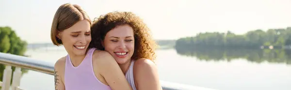 Two women share laughter while embracing in a serene park setting. — Stock Photo