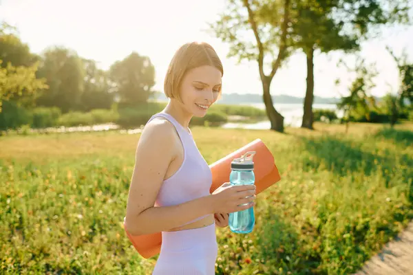 She smiles as she embraces nature with her yoga gear. — Stock Photo