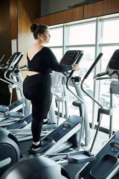 A plus-size woman confidently works out at the gym, embracing body positivity in stylish active wear. — Stock Photo